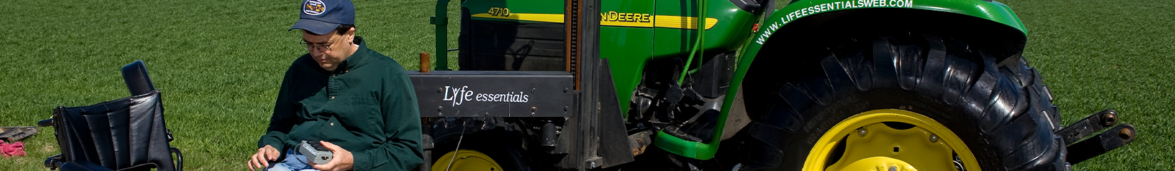 A person sitting alongside a John Deere tractor in their mobility device.